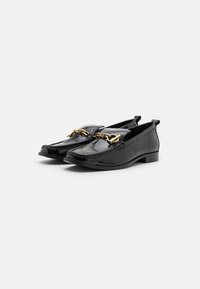 Zwarte lederen loafers met een glanzende afwerking, voorzien van gouden hardware-accenten en een lage, ronde hak voor stabiliteit.