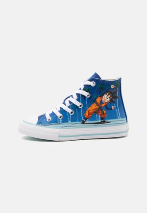Zapatilla alta azul con cordones y suela blanca, con un personaje de dibujos animados con un conjunto naranja en una pose dinámica en el lateral.
