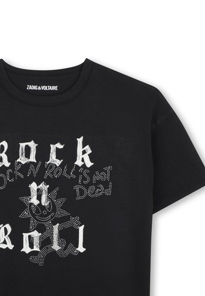 Μαύρο T-shirt με λευκό γοτθικό κείμενο "Rock n Roll" και κείμενο με τελείες "Rock n Roll is not Dead" δίπλα σε φιγούρα ηλίου με τελείες που χαμογελά.