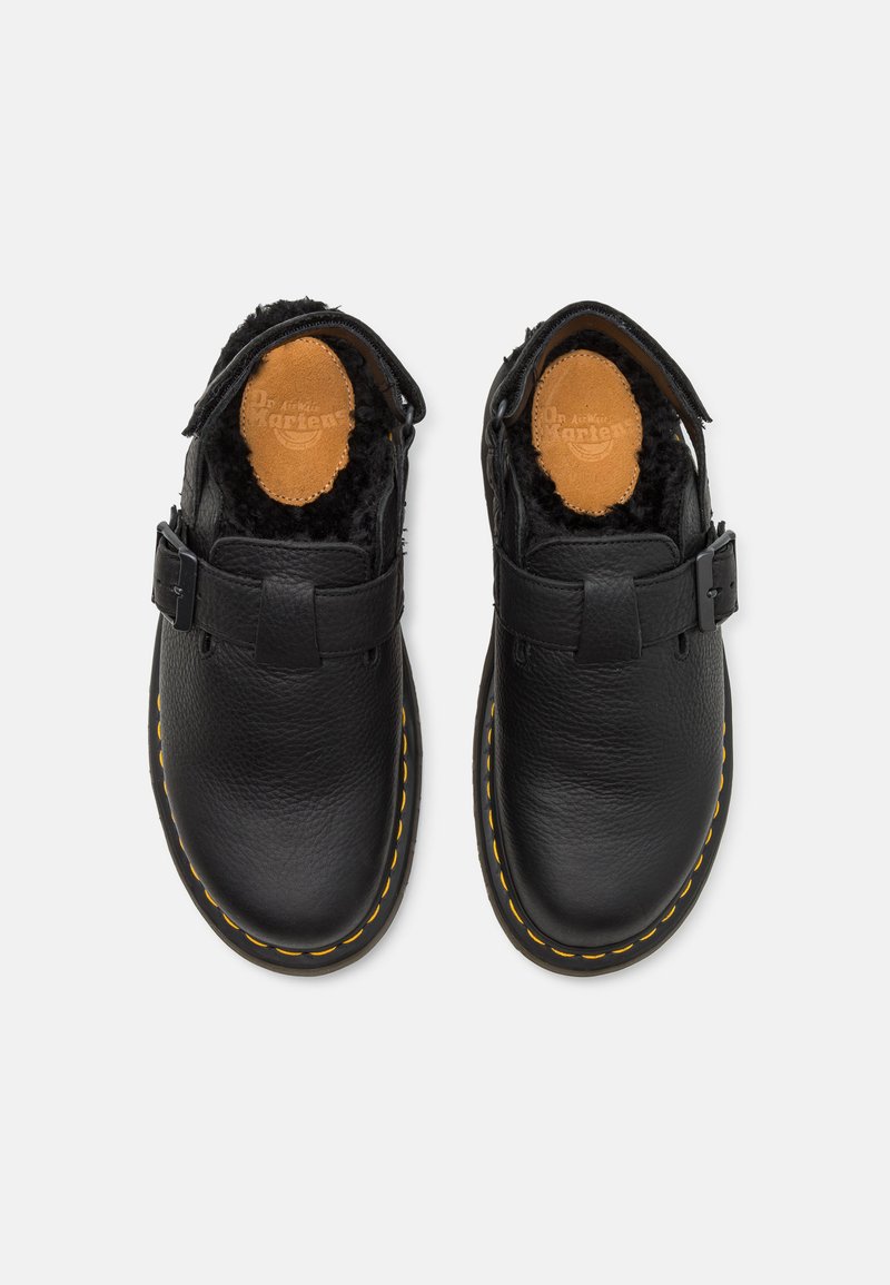 Zapatos de cuero negro con un acabado texturizado, con puntera redonda, hebilla lateral y forro de piel suave. Un pespunte amarillo contrastante resalta la suela.