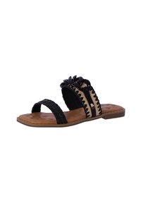 Sandalias planas negras con tiras trenzadas, una suela marrón texturizada y un adorno floral negro decorativo en la banda superior.