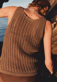 Canotta marrone a maglia realizzata in un tessuto morbido e strutturato, con scollo rotondo e orlo a coste, vista da dietro su uno sfondo naturale.