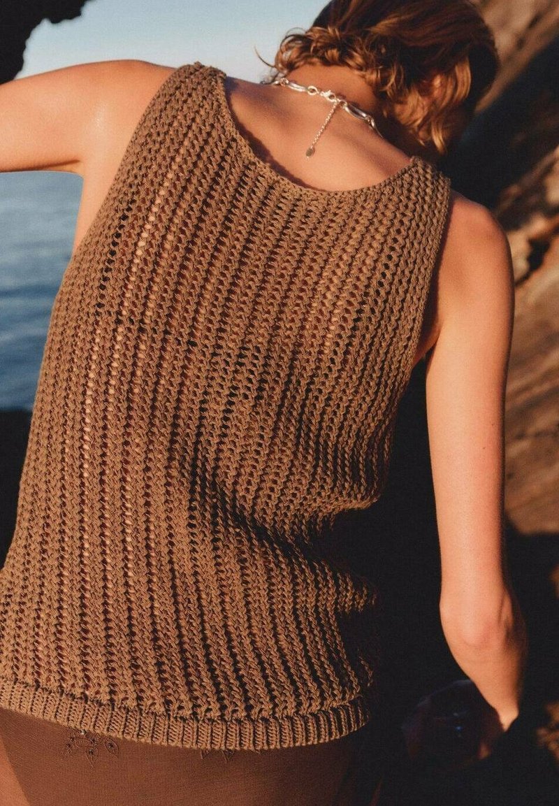 Canotta marrone a maglia realizzata in un tessuto morbido e strutturato, con scollo rotondo e orlo a coste, vista da dietro su uno sfondo naturale.