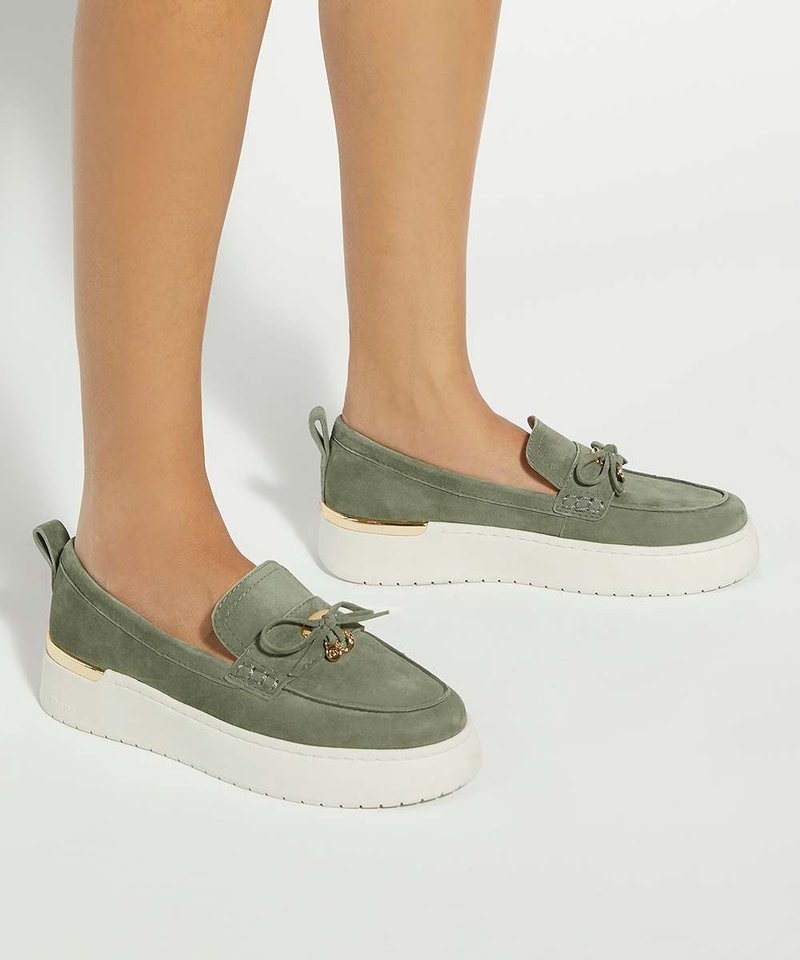 Mocassins compensés en daim vert avec semelles épaisses blanches, portés pieds nus sur un fond clair uni.