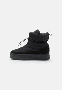 Botas de invierno negras con parte superior de tela acolchada, un cómodo cuello plegable y suelas de goma. Cuentan con un cordón para un ajuste ceñido.