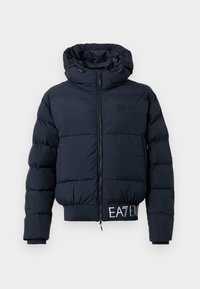 Jūras spēku puffer jaka ar rāvējslēdzēju priekšā, kapuci un elastīgu jostas vietu ar tekstu "EAT EM". Mīksts, polsterēts materiāls nodrošina siltumu.