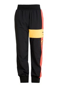 Svarta träningsbyxor med ett brett svart midjeband. Har röda och gula sidopaneler med grafiska detaljer. Tillverkade av lätt, slät tyg.