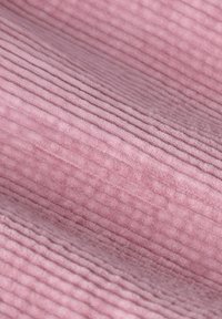 Tissu rose texturé avec un motif en côtes. La surface a une sensation douce et pelucheuse, présentant des variations subtiles de couleur et de profondeur.