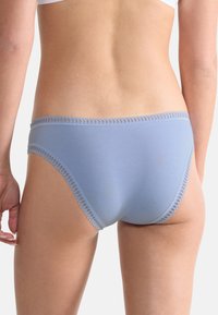 Světle modré bavlněné kalhotky s hladkým povrchem a krajkovým lemem v pase, které se těsně přiléhají a nabízejí minimální pokrytí vzadu.