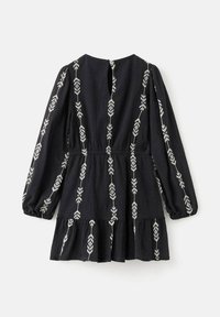 Črna obleka z dolgimi rokavi, z nabranim pasom, razširjenim robom in belimi vezenimi vzorci puščic po sprednjem delu in rokavih.