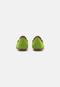 Groene suède schoenen met een gladde textuur, puntige neus en een leren voering in bruin. De zool is plat en het ontwerp is simpel en strak.