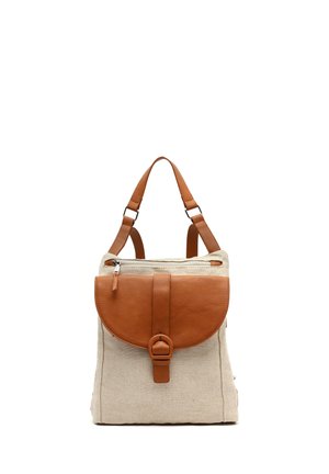 Beige stoffen rugzak met bruin lederen klep, gesp, ritstas en verstelbare schouderbanden, afgebeeld op een witte achtergrond.