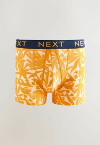 Caleçon jaune avec un motif abstrait audacieux et une ceinture élastique bleu marine arborant "NEXT" en lettres dorées. Tissu extensible.