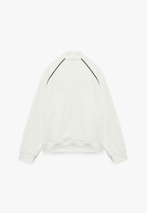 Weißes Sweatshirt mit Kragen, langen Ärmeln und schwarzen Nahtakzenten entlang der Schulternähte. Glatte Textur und lockere Passform.