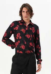 Sort skjorte med rødt blomstermotiv, lange ærmer, krave med knapper og lige skæring. Glat stof, skræddersyet pasform og moderne design.