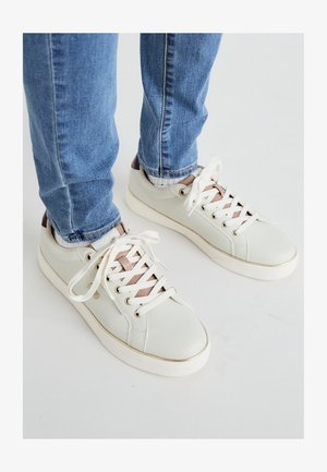 Baskets en cuir vert clair avec des lacets blancs, des accents en or rose et une finition texturée. Semelle en caoutchouc blanche et détail de talon marron.