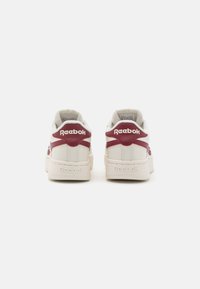 Reebok teniske s keramiko v beli barvi z maroon detajli, oblazinjenim ovratnikom in embosiranim logotipom na peti in strani.