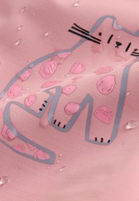 Gocce d'acqua su tessuto rosa con un semplice disegno contornato di un gatto, caratterizzato da macchie e baffi.