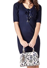 Granatowa sukienka prążkowana z krótkimi rękawami i dekoltem z wiązaniem. Trzyma białą torebkę z kwiatowym wzorem i teksturowanym uchwytem.