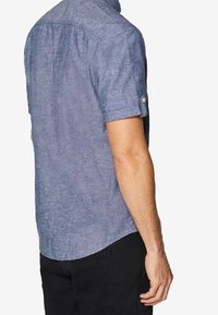 Korte mouwen navyblauw shirt van een gestructureerde stof, met een knoopdetail op de mouw en een subtiel gebogen zoom.