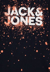 T-shirt nera con testo bianco "JACK & JONES", caratterizzata da un design a macchie di colore arancione chiaro. Il materiale sembra morbido, con una texture liscia.