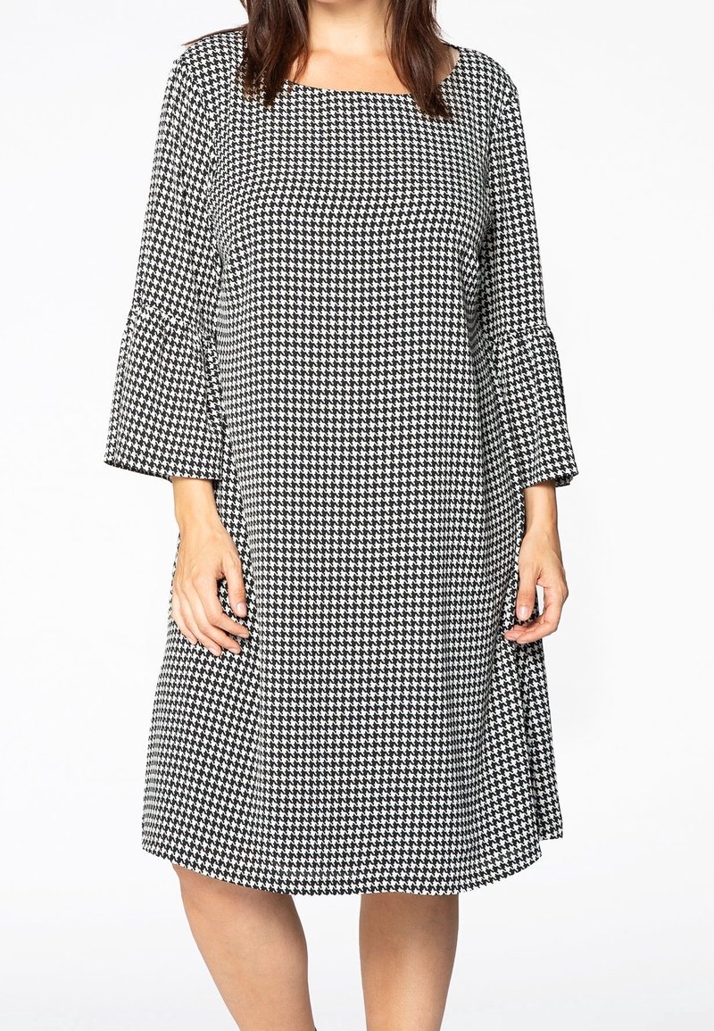 Šaty s černo-bílým skotským vzorem houndstooth, s tříčtvrtečními zvonovými rukávy a čtvercovým výstřihem, vyrobené z lehkého materiálu.