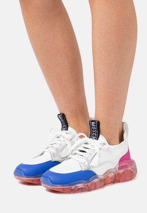 White sneaker with blue toe cap, silver accents, and pink heel; clear bubble sole. Features lace-up design and branded tongue label.