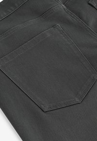 Mørkegrå stretch denim jeans med en baglomme med subtil sydetalje, glat tekstur og en tæt på fabrikken.