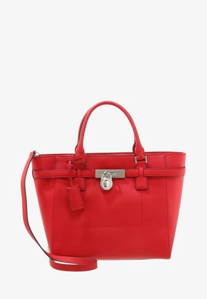 Sac à main en cuir rouge avec double poignée, une bandoulière amovible et un détail de fermeture argenté à l'avant.