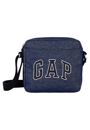 Kleine dunkelblaue Jeans-Schultertasche mit schwarzem, verstellbarem Gurt und großen, weiß umrandeten Buchstaben GAP auf der Fronttasche.