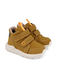 Zapatos infantiles de ante marrón tipo botín con dos correas de Velcro, detalles en naranja y suela de goma blanca. Cuenta con costuras en contraste y lengüetas.