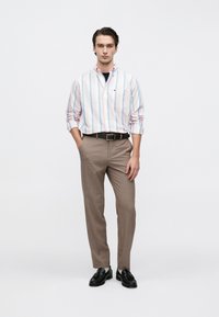 Ριγέ πουκάμισο με κουμπιά σε παστέλ χρώματα με τσέπη, σε συνδυασμό με ανοιχτό καφέ παντελόνι και μαύρα παπούτσια, με εφαρμοστή σχεδίαση.