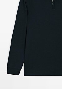 Langermig shirt van donker marineblauwe stof met een halve rits kraag en geribde manchetten. Soepele textuur en comfortabele pasvorm.