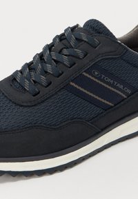 Baskets bleu marine en mesh et daim, avec des bandes contrastantes beige et des lacets assortis, semelle texturée et col rembourré.