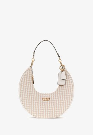 Sac à main en campagne beige en forme de croissant, avec des accessoires en or et une anse noire. Il présente un logo et deux petites étiquettes attachées.