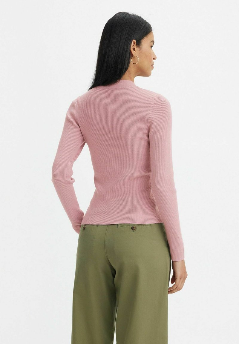 Maglione aderente a coste in rosa pallido con maniche lunghe e scollatura a girocollo, abbinato a pantaloni a vita alta verde oliva.