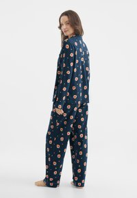 Granatowy zestaw piżamowy w truskawkowy wzór, z długimi rękawami i luźnym krojem. Miękka tkanina i zapięcie na guziki, z zabawnymi akcentami.