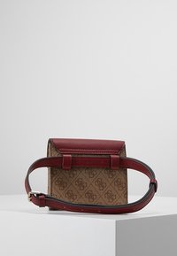 Lille håndtaske med en struktureret design, der har en bordeaux læderklap og rem, samt et mønstret brunt tekstillegeme. Justerbar rem medfølger.