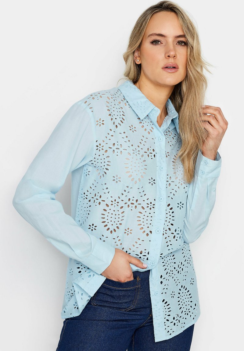 Camicia azzurra chiara con design a bottoni, caratterizzata da intricate lavorazioni a taglio, maniche lunghe e colletto appuntito, realizzata in tessuto traspirante.