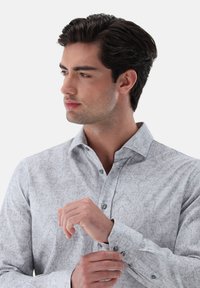 Camicia button-up grigia chiara con un sottile motivo paisley, maniche lunghe, colletto aperto e dettagli dei bottoni a contrasto.