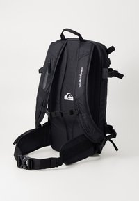 Black backpack with padded straps, multiple zippered pockets, and adjustable waist belt. Features a logo on the side, made from durable fabric.