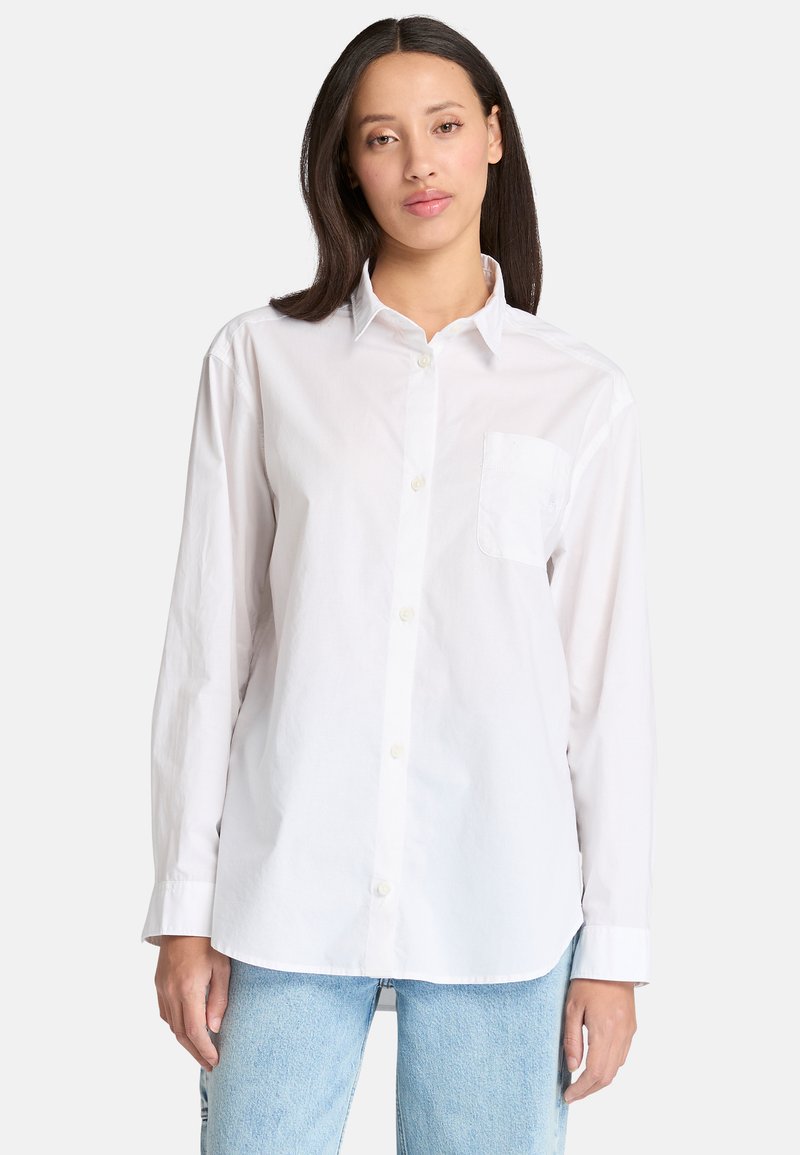 Chemise blanche à boutons en coton, dotée d'un col classique, de manches longues et d'une petite poche sur le côté gauche de la poitrine.