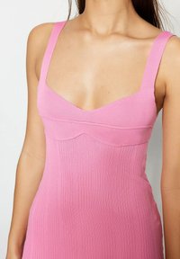 Robe en tricot côtelé rose ajustée avec de larges bretelles, un décolleté rond et des coutures subtiles le long du bodice. Texture lisse.