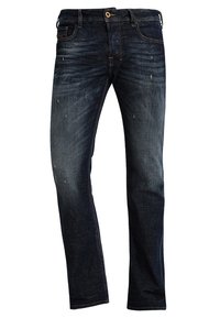 Tmavě modré džíny z denimu s mírným vyblednutím, standardní střih, design s pěti kapsami a jemné opotřebení poblíž kapes a kolen.