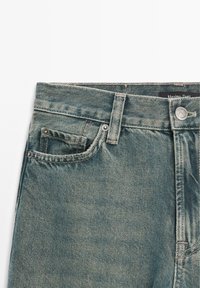 Jeans in denim blu sbiadito con vita alta, design a cinque tasche, chiusura con bottone metallico e cuciture a contrasto. Etichettati Massimo Dutti.