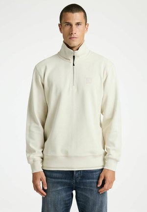Hellbeiges Sweatshirt mit Viertelreißverschluss aus weichem Material, mit kontrastierendem schwarzem Reißverschluss und kleinem Logo auf der Brust.