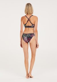 Bikini nero con motivi colorati di foglie di palma. Il top presenta un design incrociato sulla schiena; il fondo ha uno stile con gambature alte. Tessuto liscio ed elastico.
