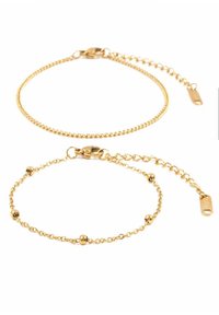 Pulseras en tono dorado con diseños de cadena únicos; una con pequeñas cuentas decorativas, la otra con una cadena de lazo suave y longitud ajustable.