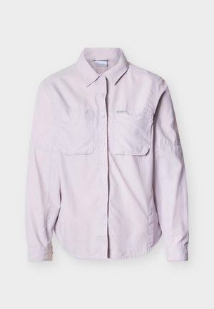 Camisa de manga larga color púrpura claro con botones, dos bolsillos en el pecho y cuello clásico, presentada sobre un fondo blanco.