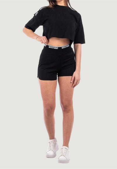 T-shirt nera corta con maniche corte, abbinata a pantaloni corti neri con un cinturino bianco Moschino. Design semplice, texture morbida.